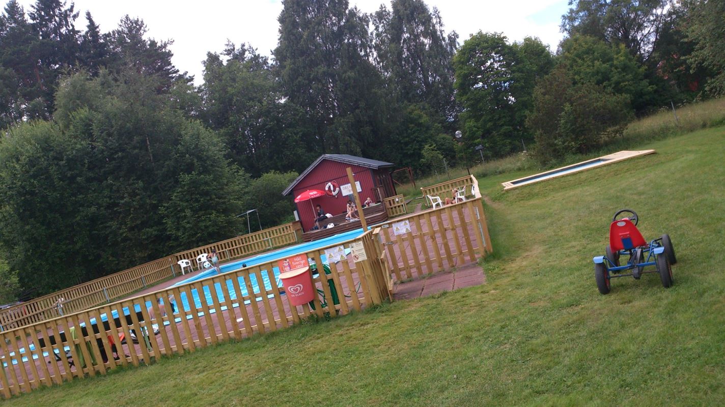 Fenced outdoor pool on a large lawn.