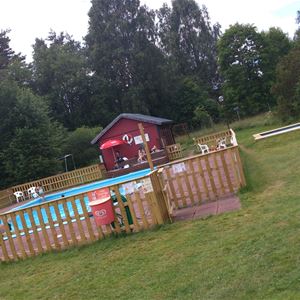 Fenced outdoor pool on a large lawn.