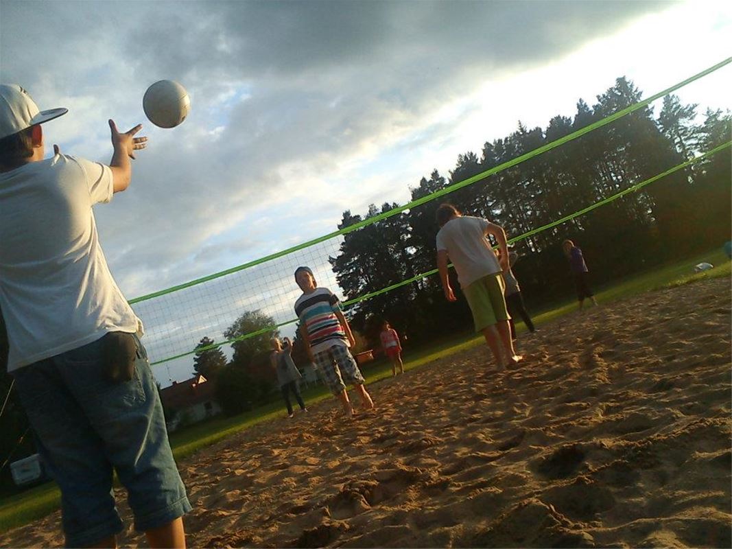 Några personer spelar volleyboll på sanden.