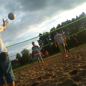 Några personer spelar volleyboll på sanden.