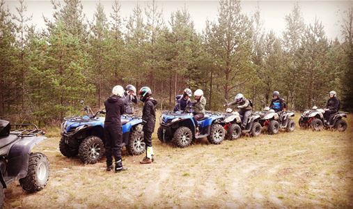 Several quad bikes in a row with drivers next to them.