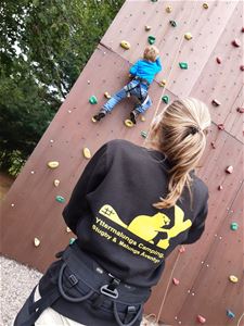 A child is climbing up for climbing wall.
