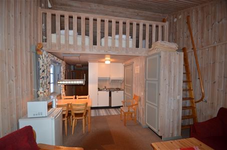 Apartment with refrigerator, microwave, dining table and a loft with beds on.
