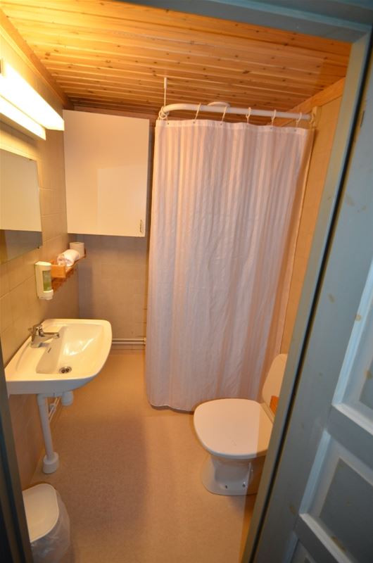 Bathroom with yellow walls, shower wit white curtains, toilet and handbasin. 