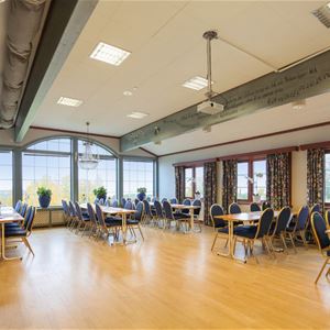 Large room with lots of windows and groups of tables and chairs. 