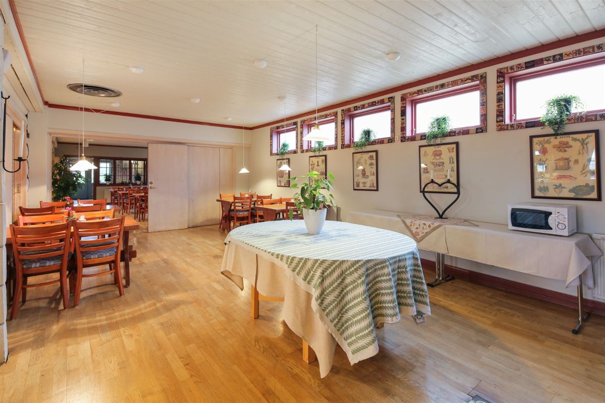 Round table with a large cloth in the middle of a large room with dining furniture in groups spread out in the room. 