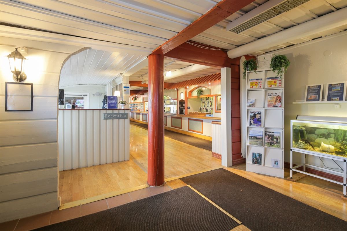 Entrance with a white reception-desk and red painted massive poles. 