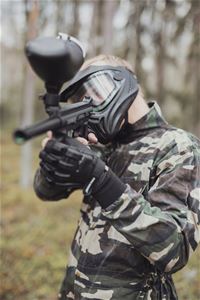 Camouflage-dressed man aiming with a paintball rifle.