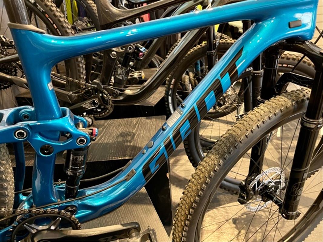 Blå cykel av märket Giant i förgrunden andra cyklar brevid, uppställda i butiken.