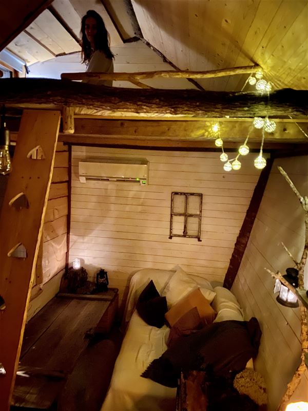 Interiör i Tiny House med timmerväggar, soffa,  ljusslingor mm.