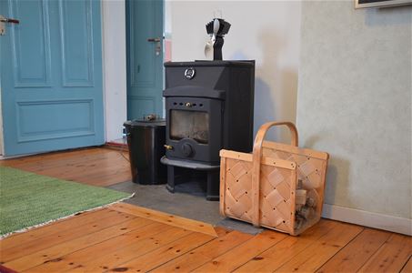 Fireplace with a wicker basket beside placed on a wooden floor.