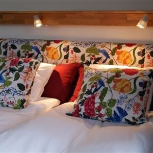 Sänggavel och kuddar i färgglatt, blommigt tyg.