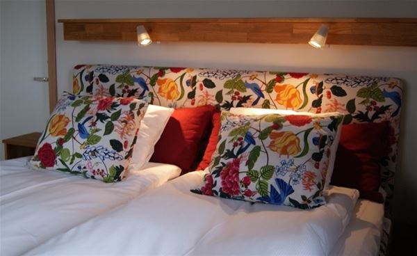 Sänggavel och kuddar i färgglatt, blommigt tyg. 