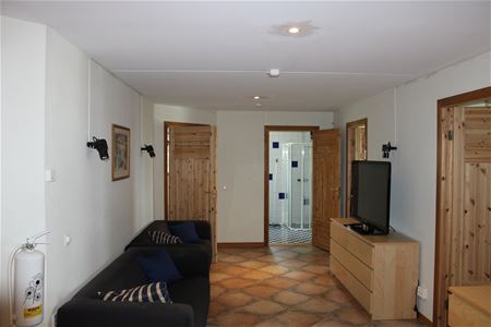Hall med tv och soffa på övre plan.