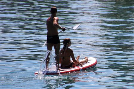 Two people on a stand up board in water.