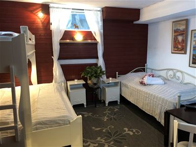 Twin room with a sibling bed and a single bed with two white bedside tables in between.