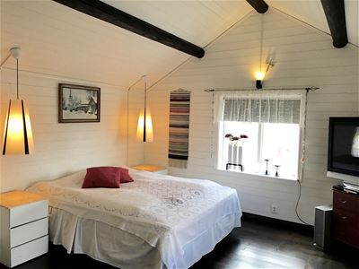 A double bed with white bedspread room has white walls and ceilings.