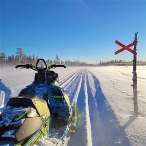 En parkerad skoter i skoterspår med en röd ledmarkeringsskylt bredvid.