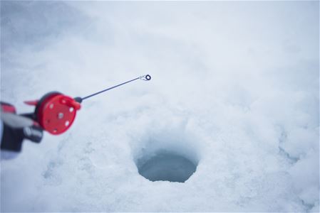 ice fishing in a hole in the ice