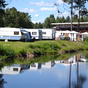 Husvagnar uppställda på camping längs en å.