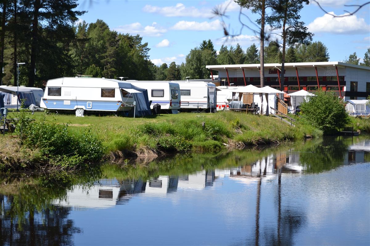 Husvagnar uppställda på camping längs en å.