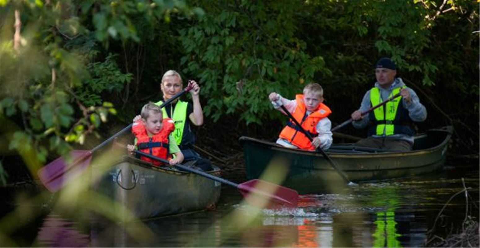 Familj som paddlar kanot i å.