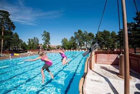 Barn som hoppar ner i utomhuspool.
