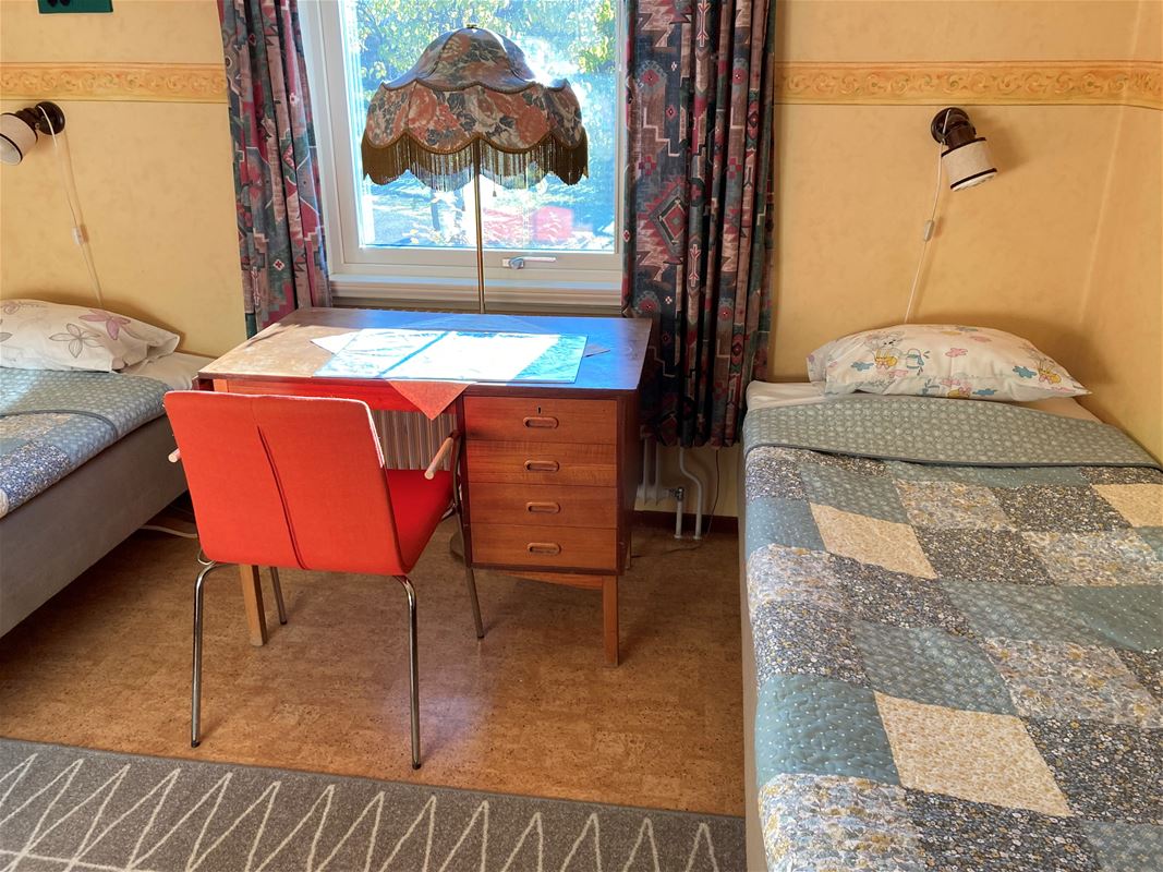 Two beds with a desk in between and a window.