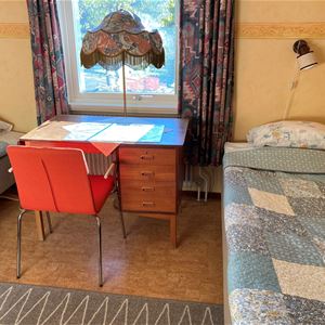 Two beds with a desk in between and a window.
