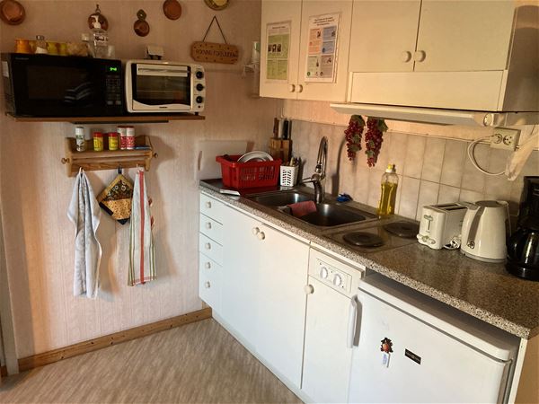 Köksavdelning med diskbänk och spis samt diverse köksredskap på bänken.  