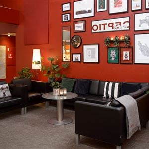Lobby, röda väggar med olika tavlor, svarta skinnmöbler.