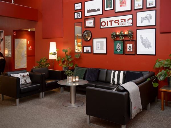 Lobby, röda väggar med olika tavlor, svarta skinnmöbler. 