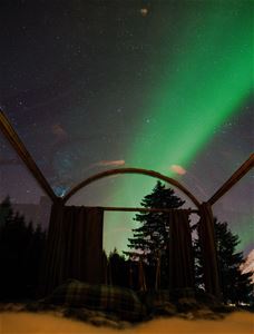 glass cabin with northern lights above