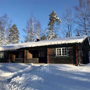 Timber cottage in snow landscape and blue sky. 