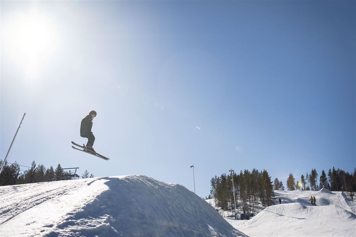 A skiier jumping, the sun is skining, blue sky.