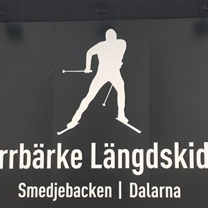 Logga med en målad person som åker längskidor och text Norrbärke längdskidor.