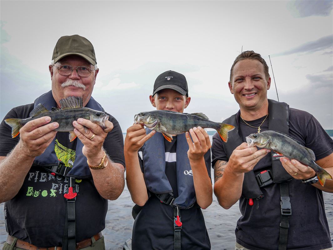 Tre fiskare med sin fiskefångst i händerna.