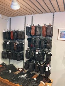 Många skinnhandskar upphängda på vägg i butiken. 