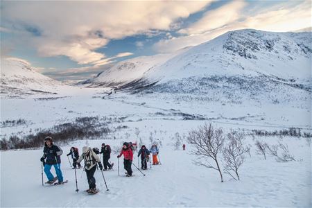 People hiking in snow-covered mountains wearing winter gear.