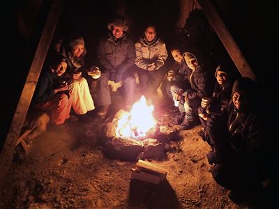 8 personer rundt ett bål på natten.