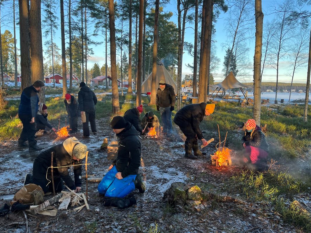En grupp förbereder eldar för matlagning utomhus.