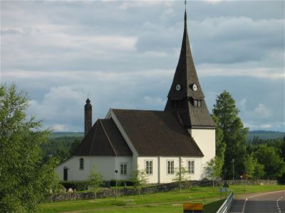 Venjan's church in the summer with mountains on the horizon.