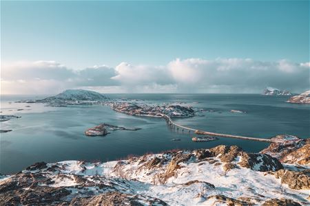 Snødekt kystlandskap med broer mellom øyer og klar himmel i bakgrunnen