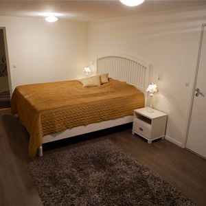 Double bed with yellow bedspread and a dark carpet on the dark floor.