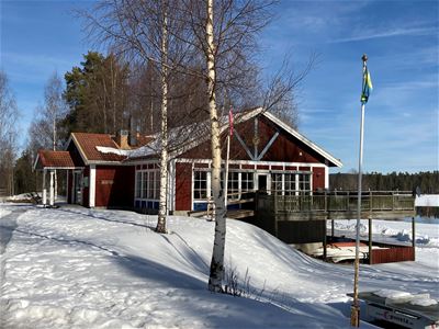 Red building with birches and flagpole in front in winter attire.