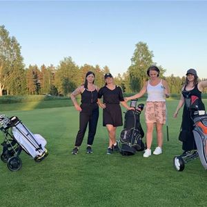 Damer med sina golfbagar på golfbanan. 
