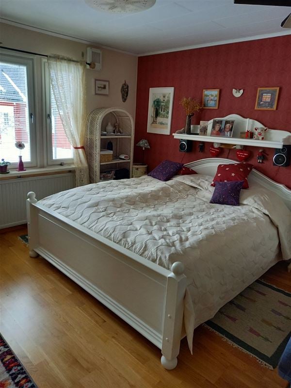 Double bed with white bedframe and a white bedspread.