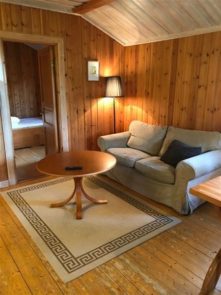 Beige soffa med runt bord i ett rum med väggar, golv och tak av furu. 