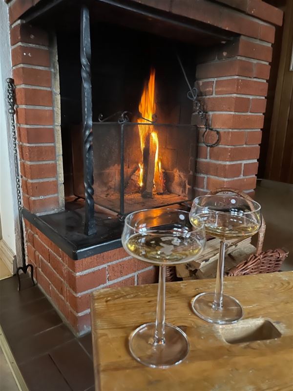 Fire in the open fire place and two glasses of wine in front. 