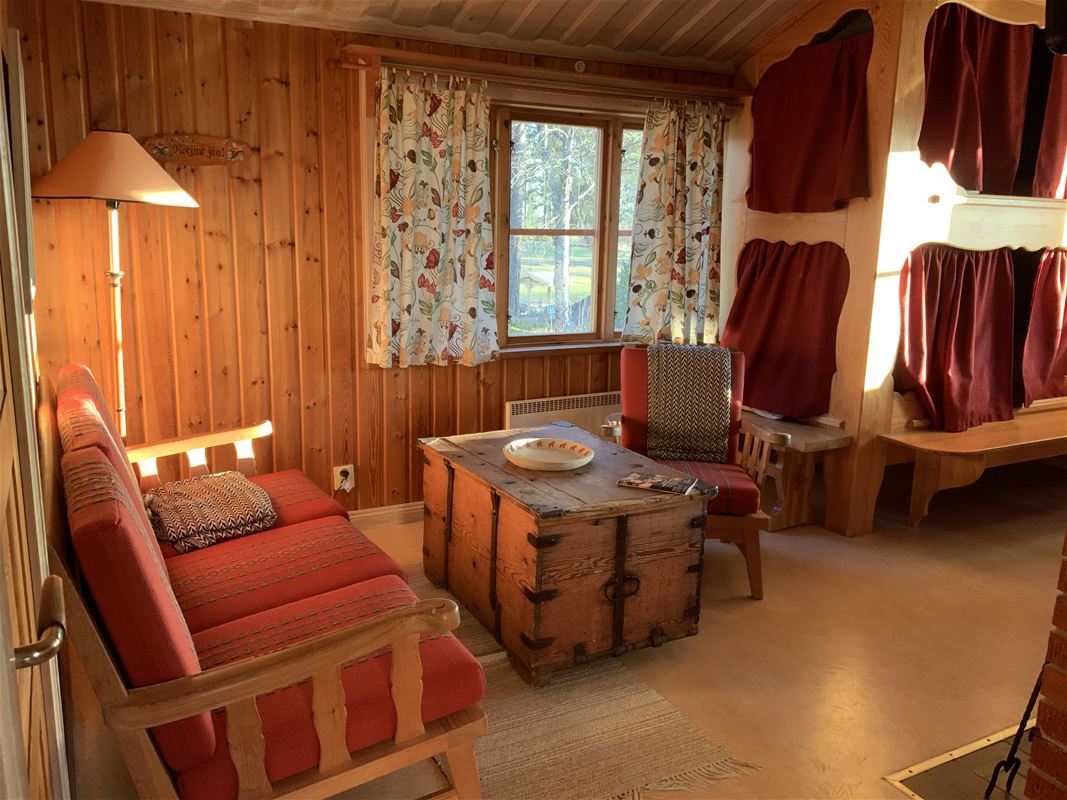 Site-built bunkbed with red curtains, red sofa and a coffin as a coffee table.